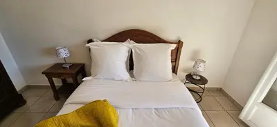 a bedroom with a bed with white sheets and pillows at T2 Paisible Quartier Vigna Majo, Olmeto in Olmeto