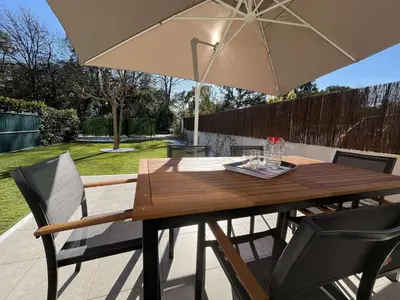 a wooden table with an umbrella on a patio at Appartement jardin à deux pas de la mer Classé 3 étoiles in Poggio-Mezzana