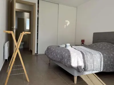 a bedroom with a bed and a wooden tripod at Appartement jardin à deux pas de la mer Classé 3 étoiles in Poggio-Mezzana
