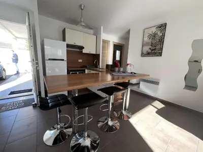 a kitchen with a wooden counter and bar stools at Appartement jardin à deux pas de la mer Classé 3 étoiles in Poggio-Mezzana