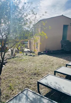a yard with two picnic tables in front of a building at Maison Murato in San-Giuliano