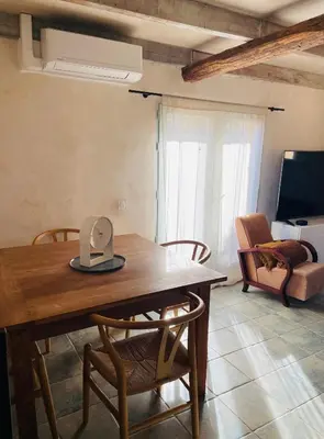 a dining room table with chairs and a television at Maison Murato in San-Giuliano
