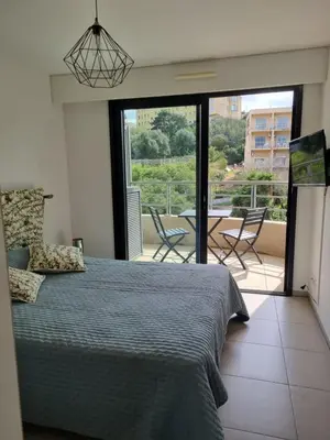 a bedroom with a bed and a balcony with a table and chairs at MAGNIFIQUE APPARTEMENT LES PIEDS DANS L'EAU PROPRIANO in Propriano