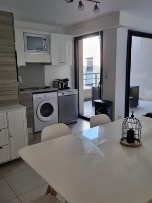 a kitchen with a table with chairs and a dishwasher at MAGNIFIQUE APPARTEMENT LES PIEDS DANS L'EAU PROPRIANO in Propriano