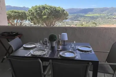 a table with plates and glasses on it with a view at Appartement 4 pers vue sur la baie de Santa Giulia in Porto-Vecchio