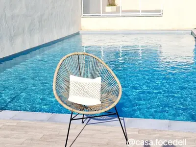 a wicker chair sitting in front of a swimming pool at Résidence Confort avec Piscine - Proche des plages in Bonifacio
