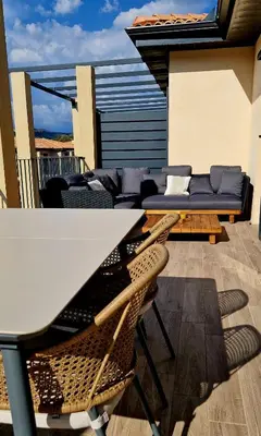 a patio with a table and chairs and a couch at Résidence Confort avec Piscine - Proche des plages in Bonifacio