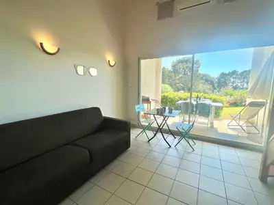 a living room with a black couch and a patio at Appartement Bella Vista 302 Porticcio in Porticcio