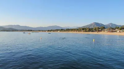 a body of water with a beach and mountains in the background at Appartement Bella Vista 302 Porticcio in Porticcio