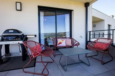 a balcony with chairs and a table and a grill at Joséphine - Appt vue exceptionnelle Porto-Vecchio in Porto-Vecchio