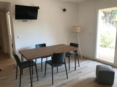 a dining room table with chairs and a television on a wall at Résidence Fiori di Cala Rossa in Lecci