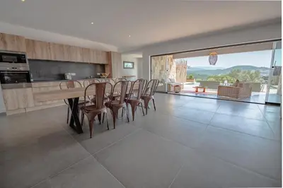 a kitchen with a table and chairs and a large window at NOUVEAUTE! Magnifique villa à 2 minutes des plus belles plages de la rive sud in Porticcio