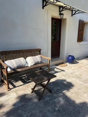 a wooden bench with two pillows sitting in front of a building at Maison de village in Manso