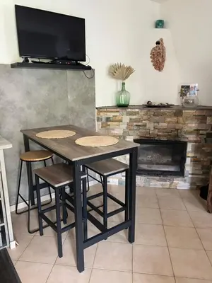 a dining room table with stools and a tv at Maison de village in Manso