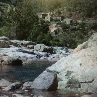 a painting of a beach with rocks and water at Maison de village in Manso
