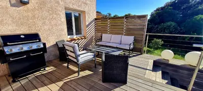 a patio with a grill and chairs on a deck at Villa Bella Vista, 4ch, piscine in Figari