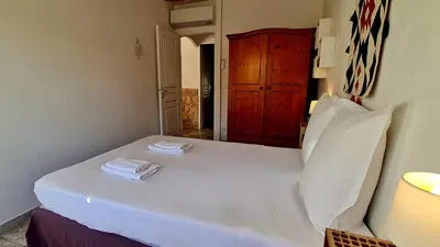 a bedroom with a white bed with a red door at Villa Bella Vista, 4ch, piscine in Figari