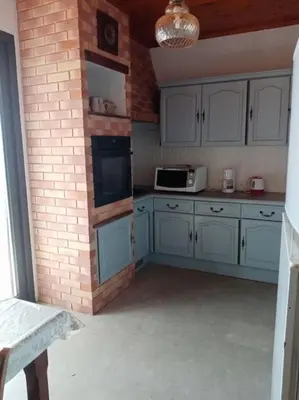 a kitchen with white cabinets and a brick wall at Maison individuelle au calme in Valle-di-Mezzana