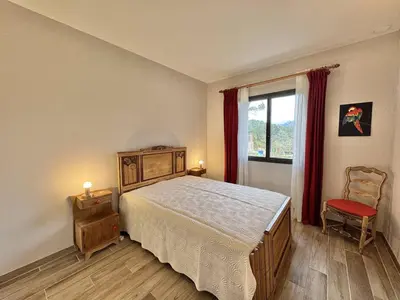 a bedroom with a bed and a window and a chair at Maison entre les montagnes à Levie in Levie