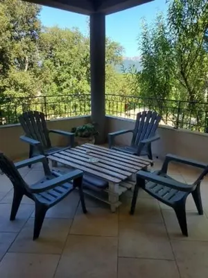 two chairs and a wooden table on a porch at Maison entre les montagnes à Levie in Levie