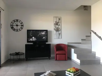 a living room with a television and a red chair at Porto vecchio - St.cyprien - Corse du sud -plages in Lecci