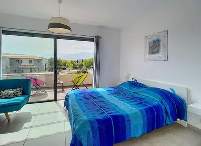a bedroom with a blue bed and a balcony at Porto vecchio - St.cyprien - Corse du sud -plages in Lecci