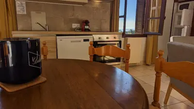 a kitchen with a wooden table and a kitchen with a stove at Le Porto T3 55m2 vue mer immeuble traditionnel en pierre de taille avec prestations exceptionnelles barbecue ordinateur vidéosurveillance terrasse panoramique in Porto Ota