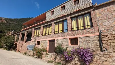 a brick building with yellow windows and purple flowers at Le Porto T3 55m2 vue mer immeuble traditionnel en pierre de taille avec prestations exceptionnelles barbecue ordinateur vidéosurveillance terrasse panoramique in Porto Ota
