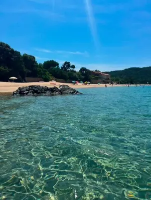 a body of water with a beach and a group of people at La vallee 3 in Belvédère