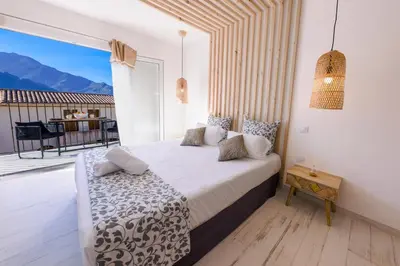 a bedroom with a bed and a balcony with a table at La Manufacture D'oriano LES NUITS AU VILLAGE in Montegrosso