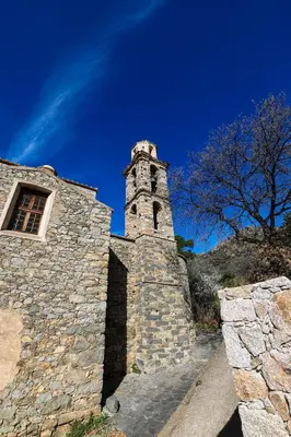a stone building with a clock tower on a hill at La Manufacture D'oriano LES NUITS AU VILLAGE in Montegrosso