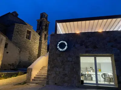 a building with a clock on the side of it at La Manufacture D'oriano LES NUITS AU VILLAGE in Montegrosso