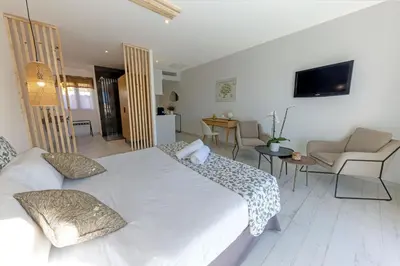 a bedroom with a white bed and a living room at La Manufacture D'oriano LES NUITS AU VILLAGE in Montegrosso