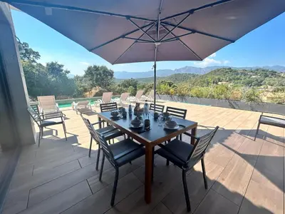 a table with chairs and an umbrella on a patio at Villa Trinita Paradis privé piscine et loisirs in Porto-Vecchio