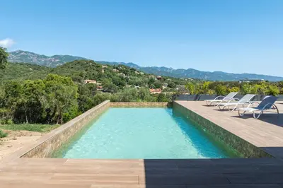 a swimming pool with chairs and a view of the mountains at Villa Trinita Paradis privé piscine et loisirs in Porto-Vecchio