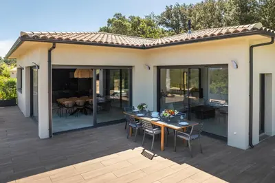a patio with a table and chairs on a deck at Villa Trinita Paradis privé piscine et loisirs in Porto-Vecchio