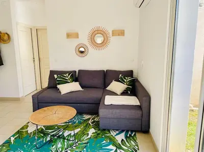 a living room with a couch and a table at Rez de Jardin Piscine et Plage in Poggio-Mezzana