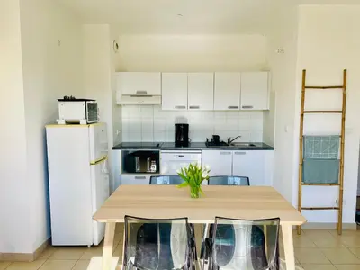 a kitchen with a table and a white refrigerator at Rez de Jardin Piscine et Plage in Poggio-Mezzana