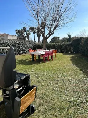 a table and chairs and a television in a yard at Rez de Jardin Piscine et Plage in Poggio-Mezzana