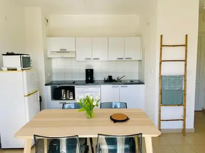 a kitchen with a wooden table with chairs and a counter at Rez de Jardin Piscine et Plage in Poggio-Mezzana