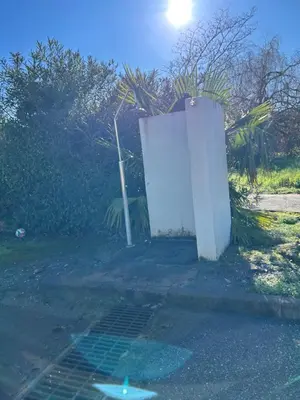 a white wall and a drain in a yard at Rez de Jardin Piscine et Plage in Poggio-Mezzana
