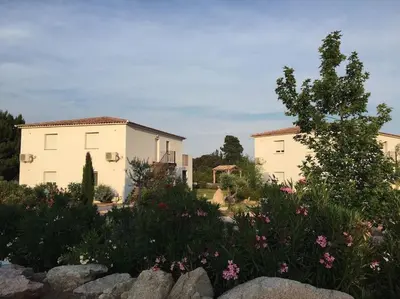 a view of two buildings in a garden with flowers at Appartement 4 Pers - Cala Rossa - Piscine in Lecci