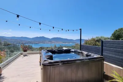a hot tub on a deck with a view of the water at Maison avec jacuzzi in Olmeto