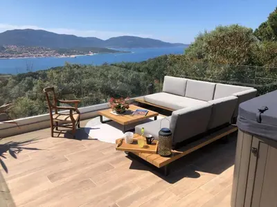 a couch and a table on a patio with a view at Maison avec jacuzzi in Olmeto