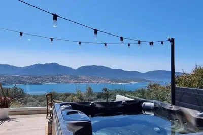 a hot tub on a patio with a view of the water at Maison avec jacuzzi in Olmeto