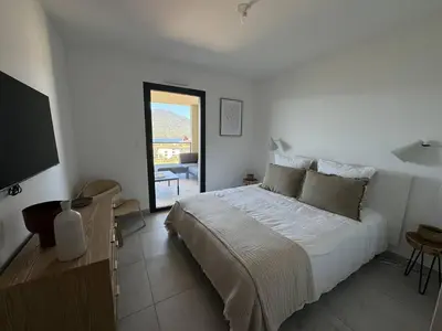 a white bedroom with a bed and a television at Appartement tout confort vue mer in Propriano