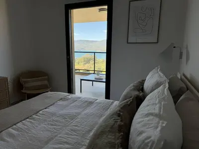 a bedroom with a bed and a door to a balcony at Appartement tout confort vue mer in Propriano
