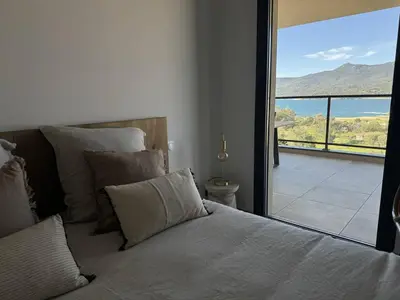a bedroom with a bed with a view of a balcony at Appartement tout confort vue mer in Propriano