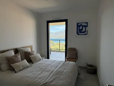 a bedroom with a bed with a view of the ocean at Appartement tout confort vue mer in Propriano