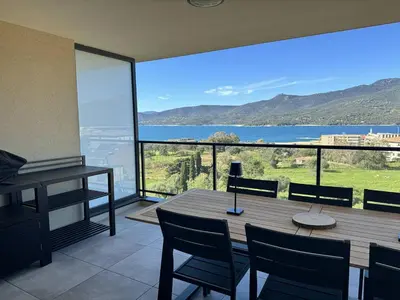 a dining room with a table and chairs and a view of the water at Appartement tout confort vue mer in Propriano